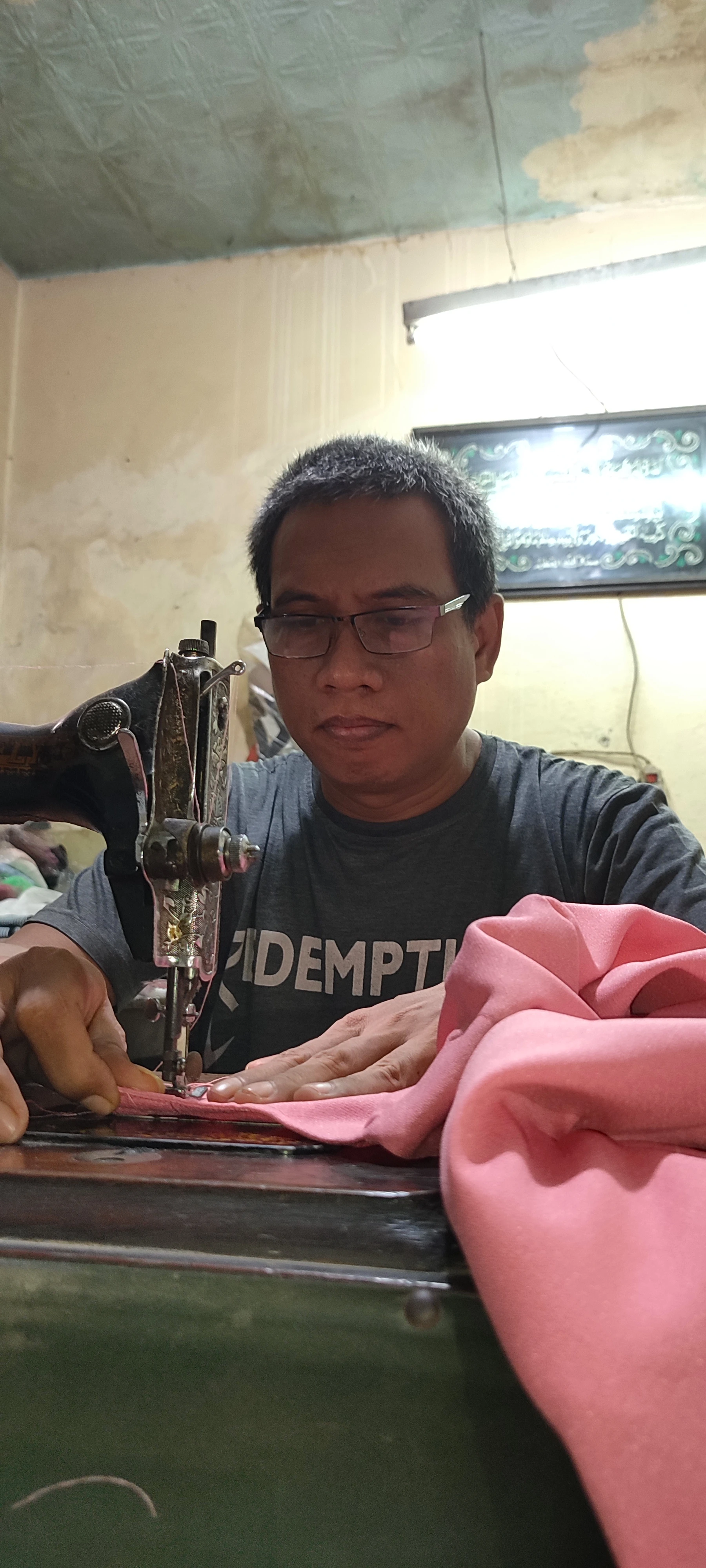 Pak Deni, penjahit spesialis di Condet yang telah berpengalaman sejak tahun 1990-an dalam pembuatan pakaian pria dan wanita
